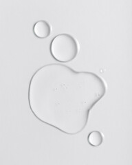 Transparent cosmetic serum drops on a light background