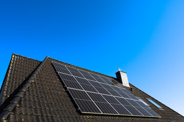 Solar panels producing clean energy on a roof against blue sky