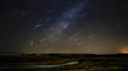A meteor shower streaking across a dark sky, illuminating the landscape below.