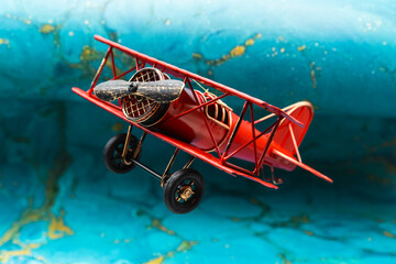 Avión biplano clásico pintado de rojo de hélice, con fondo azul abstracto