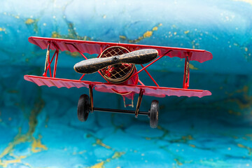 Avión biplano clásico pintado de rojo de hélice, con fondo azul abstracto