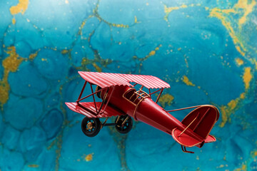 Avión biplano clásico pintado de rojo de hélice, con fondo azul abstracto