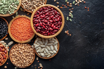 Fototapeta premium Various legumes, overhead flat lay shot. Many different pulses, an assortment. Plant-based vegan protein, top shot on a black background