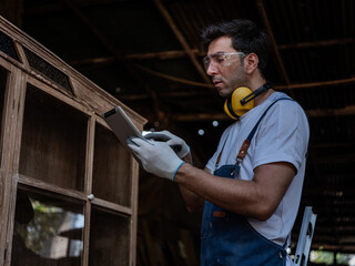 Professional Carpenter use tablet  working to making woodcraft furniture in wood workshop look...