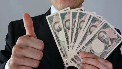 新一万円札を持ちポーズをするビジネスマン