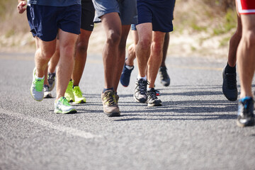 Fototapeta premium People, shoes and group running in road for marathon practice, endurance training and fitness jog. Legs, low angle and athlete with race exercise for performance, sports challenge and healthy body