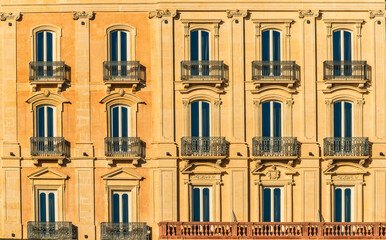 old yellow facade of house with windows and balconies in italian vintage style
