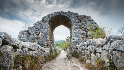 Mysterious portal, path through gray rocky stones. Ancient architecture. Natural scenery. Old arch.