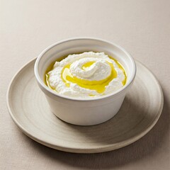 A small bowl of whipped ricotta with a drizzle of olive oil, set on a neutral ceramic plate.