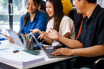 Five young Asian professionals collaborate at startup business meeting, working at desk with...