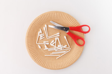 A set of crafting materials arranged on a flat surface, including scissors, a paper plate, cotton swabs, Perfect for DIY crafting, tutorials, and creative projects. Ideal for blogs, and educators