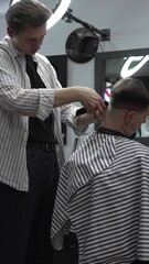 Professional barber grooming client's hair using electric clipper, delivering precise cut with skill in contemporary salon setting