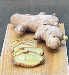 Fresh ginger is cut into pieces and placed on a wooden cutting board ready for cooking.