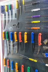 Variety of colourful kitchen knives displayed on a pegboard in a shop