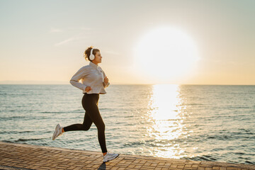 Young caucasian woman run or jog on the beach at sunset