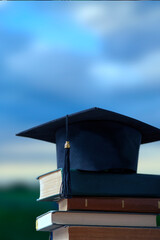 Stacks of books, Square academic cap or graduation hat against the sky. Concept of education,...