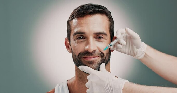 Cosmetologist, hands and face of man with injection in studio for wrinkles, antiaging or facial treatment. Plastic surgery, needle and nurse with male person for filler syringe by gray background.