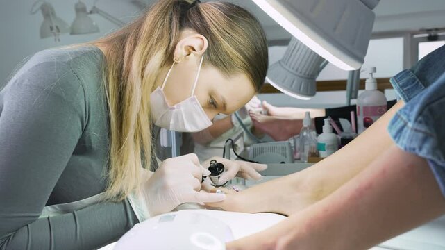 Group of professional podiatrists working in a modern nail beauty studio or spa. Satisfied clients relaxing and enjoying in a great foot and toenails treatment. 