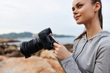 Young woman with a camera on the beach, showcasing photography passion and creativity in a serene...