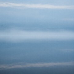 Obraz premium A serene lake covered in mist, blending the water and sky into a seamless, tranquil blue landscape with soft, dreamy reflections. 
