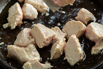 Chicken fillet pieces are fried in a frying pan in oil