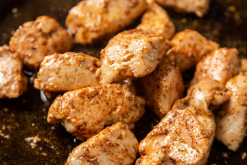 Chicken pieces are fried in a frying pan in sauce and spices.