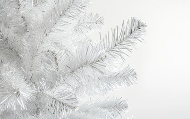 Close-up of white Christmas tree with silver ornaments and tinsel on white background, soft shadows and sharp focus