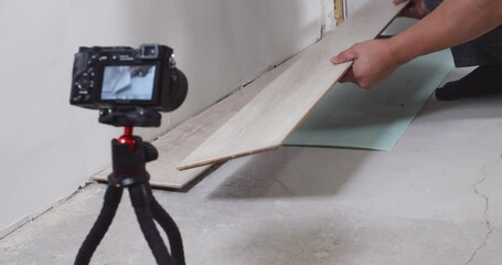 Construction workers lay laminate flooring planks in a house undergoing renovation. The process showcases skillful installation and attention to detail in home improvement