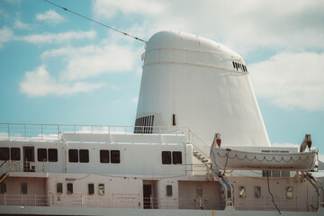 Close-up of an old passenger ship with a large white funnel, multiple windows, rusted railings, and...