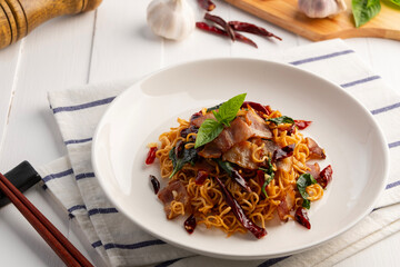 Stir Fried instant noodle With Dried Chili and Crispy Bacon on white plate.Fusion food.