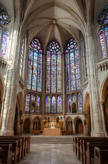 Obraz premium Majestic Cathedral: Explore the grandeur of a cathedral, featuring intricate stained-glass windows that cast vibrant hues upon the interior. Rows of wooden pews lead to an altar.