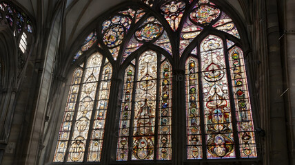 Obraz premium Gothic Cathedral Stained Glass Window: A breathtaking view of an ancient Gothic cathedral's stained-glass window, showcasing intricate designs and vibrant colors, bathed in soft, diffused light.