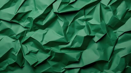 Crumpled emerald green wrapping paper displaying intricate folding patterns, generating textured abstract background with dynamic light and shadow interplay