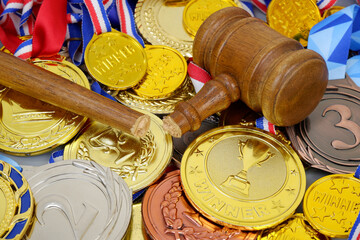 Broken judge gavel on gold medals background, sport court concept.