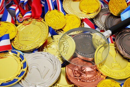 Magnifying glass on gold medals background. Sport results review concept.
