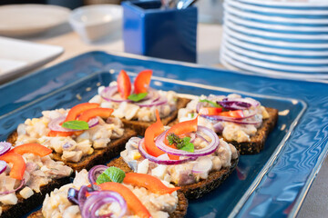 Appetizer food, open sandwich with herring and red onion. Open sandwiches with herring, red onion and paprika. Coffee break, catering a business meeting. Fish sandwiches at business event catering.