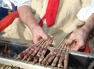 hands of the cook turning the meat skewers called ARROSTICINI which are a typical dish of the...