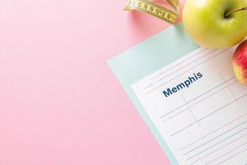 Meal Plan Sheet with Tape on Pink Background &ndash; Healthy Eating Concept with Apple and Measuring Tape for Nutrition and Diet Planning







