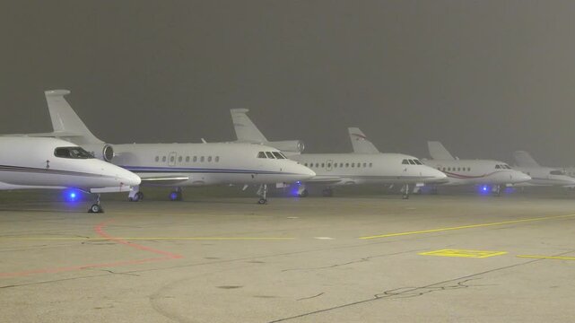 private jets lined up apron tarmac parking position foggy night scene reflects wealth luxury associated these aircraft fbo gat areas airport stands zurich 