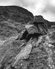 The photograph captures a prominent rock structure in a hilly region, with minimal plant life and...