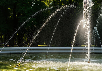 Fototapeta premium Decorative fountain splashing refreshing water in a city park during summer heat