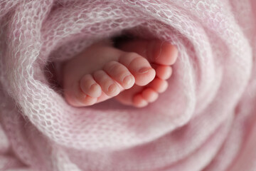 Baby foot on pink soft coverlet, blanket.Close-up of tiny, cute, bare toes, heels and feet of a newborn girl, boy.Detail of a newborn baby legs. Macro horizontal professional studio photo. 