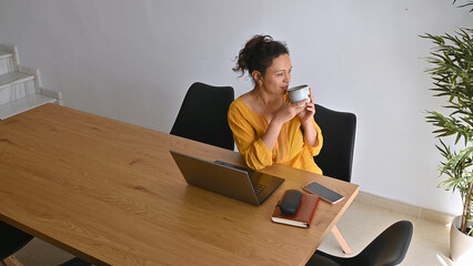 Woman Entrepreneur Working Remotely and Sipping Coffee in Modern Home Interior