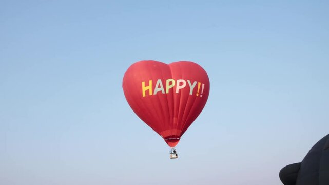Handheld Red Heart Shape Hot Air Balloon on Sky Background. Funny Balloon Festival Activity