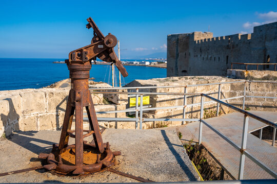 Old artillery mechanism on the fortress walls of Kyrenia in Northern Cyprus. The aged military relic stands against the backdrop of the sea and historic castle, symbolizing the island turbulent past - Powered by Adobe