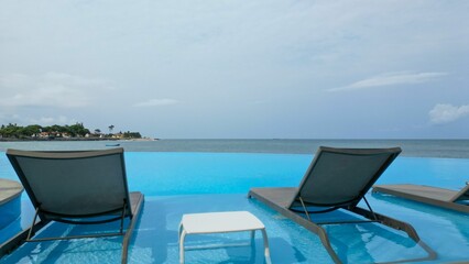 View of infinity pool with chairs and a table in Sao tome