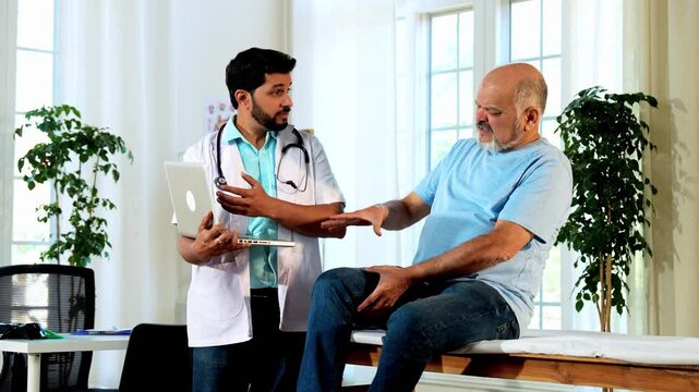 Indian Asian male doctor explaining knee-related diagnosis, possible treatments, and precautions to a senior old-aged male patient in his OPD, ensuring clarity and quality healthcare in a cozy clinic 