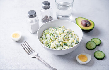 Egg cucumber avocado salad with mayonnaise sauce in a bowl