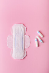 Menstrual pad and tampons on pink background, top view.