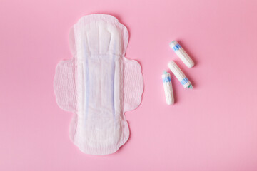Menstrual pad and tampons on pink background, top view.